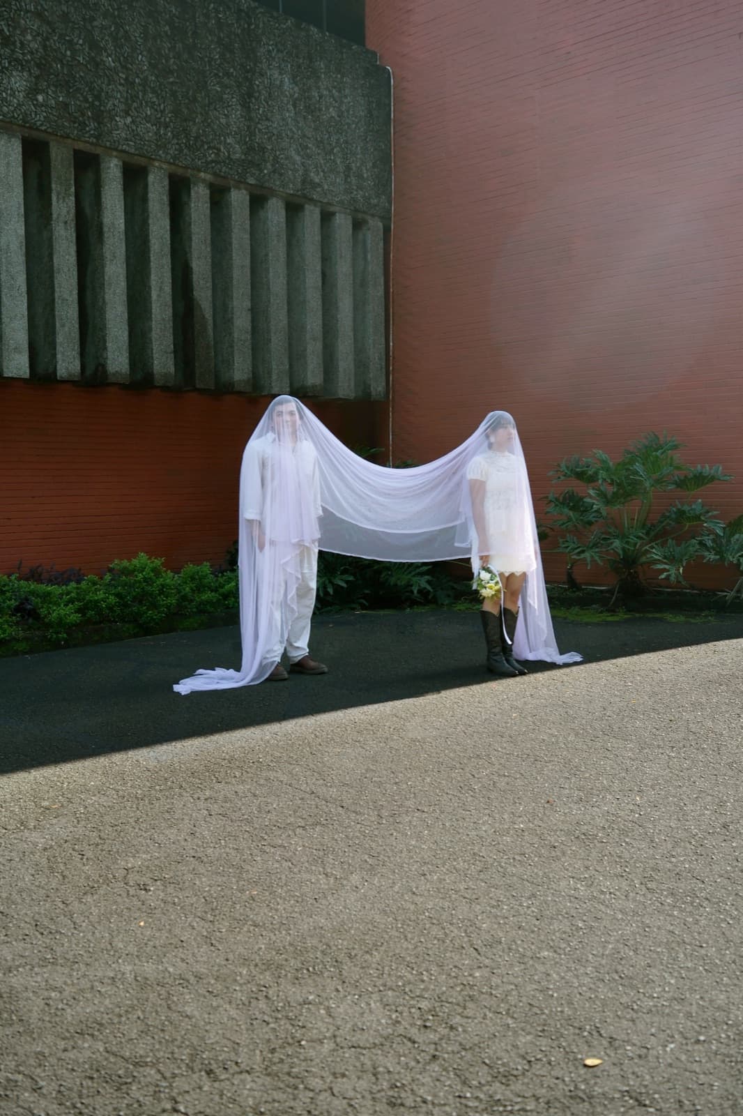 The couple beneath a shared veil outside Holy Family Chapel