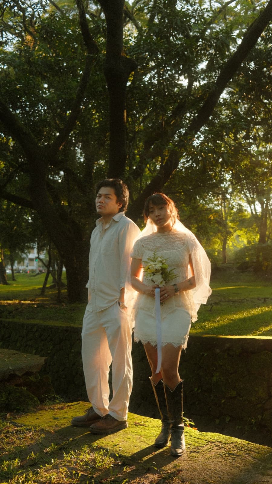 The couple standing together under the trees