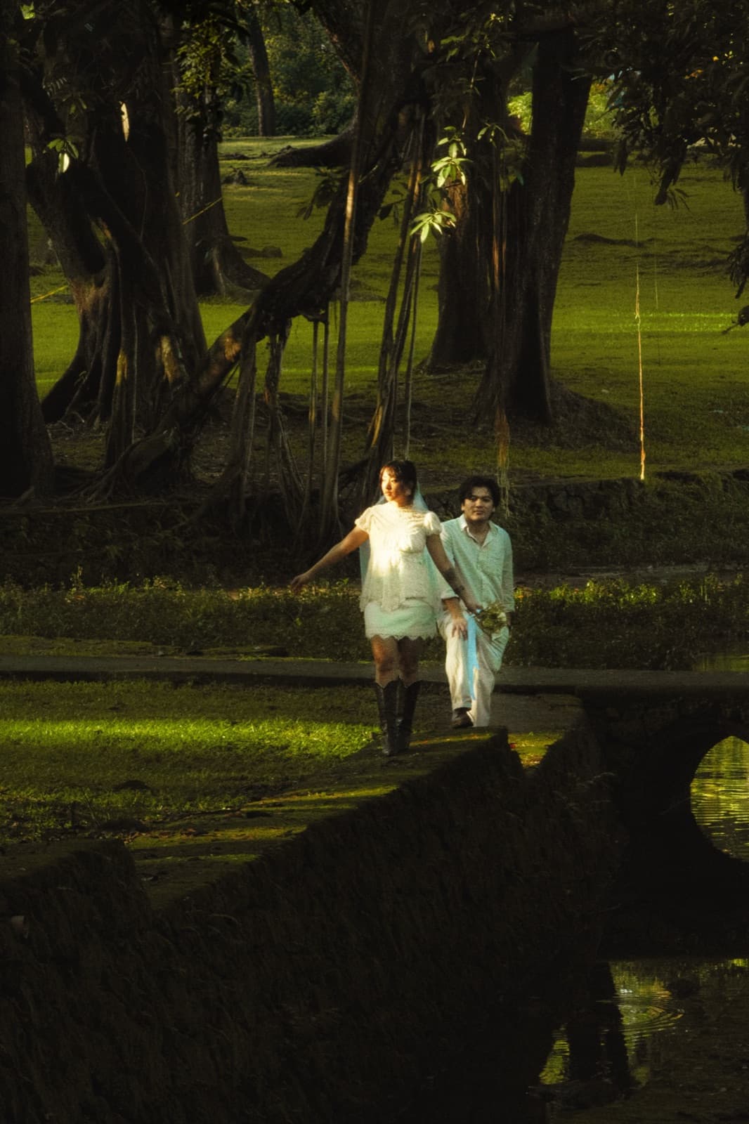 The couple walking across a garden bridge