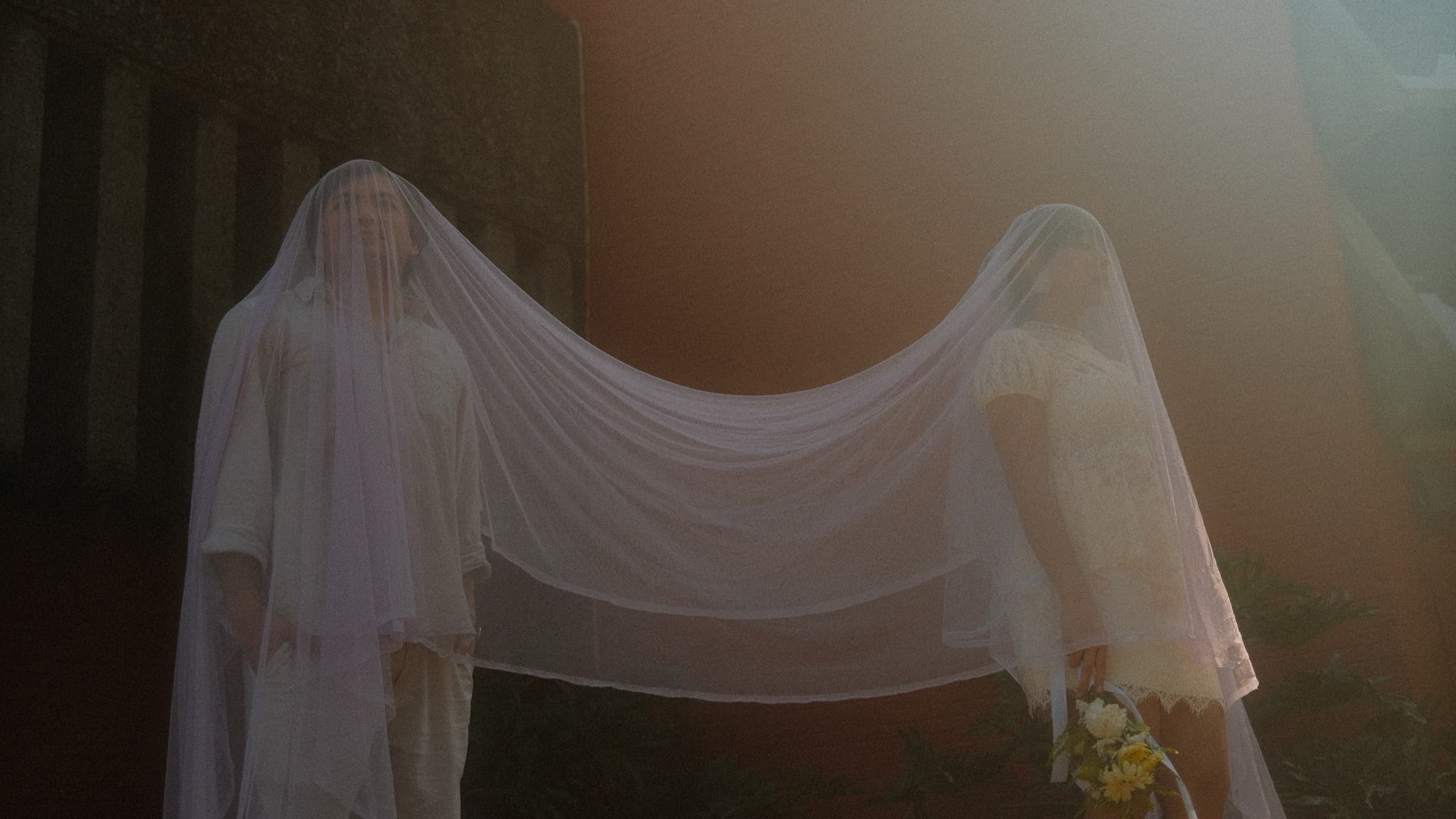 The couple standing beneath a long shared veil