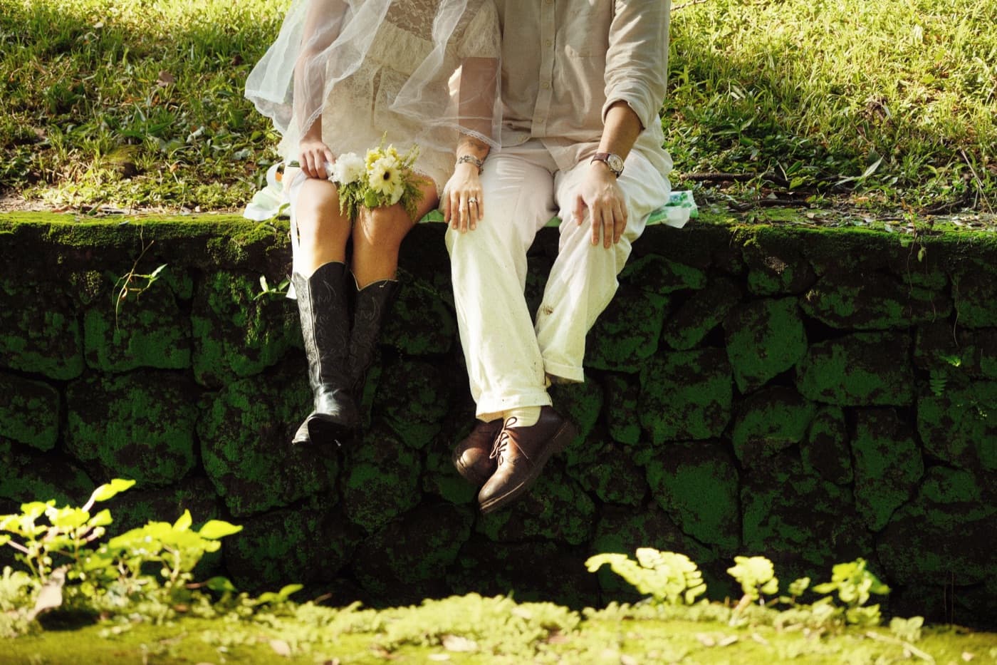 The couple sitting side by side on a mossy stone wall